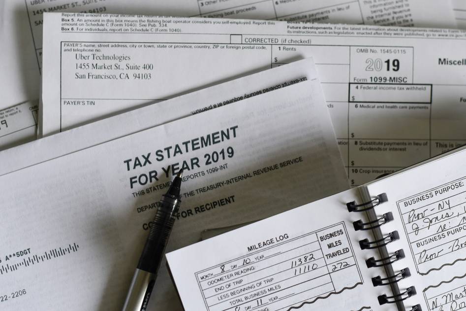 A person reviewing tax documents with a checklist and laptop
